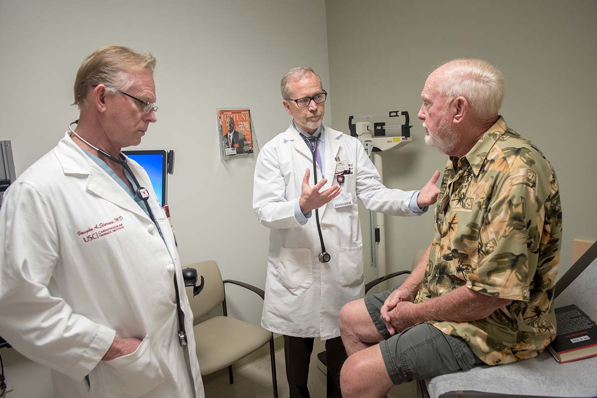 Two Keck Medicine of USC Cardiac and Vascular Institute doctors talk to a patient in an examining room