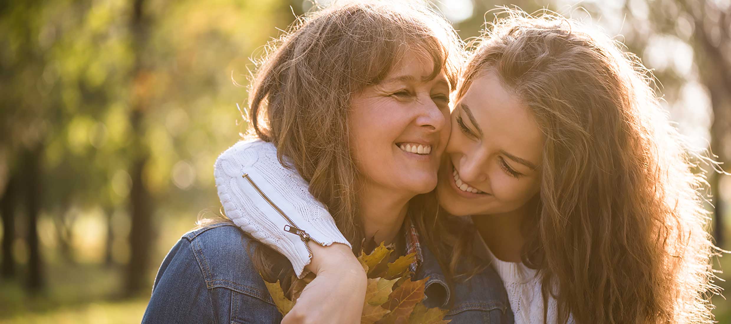 Mother and daughter smile and embrace while walking outdoors