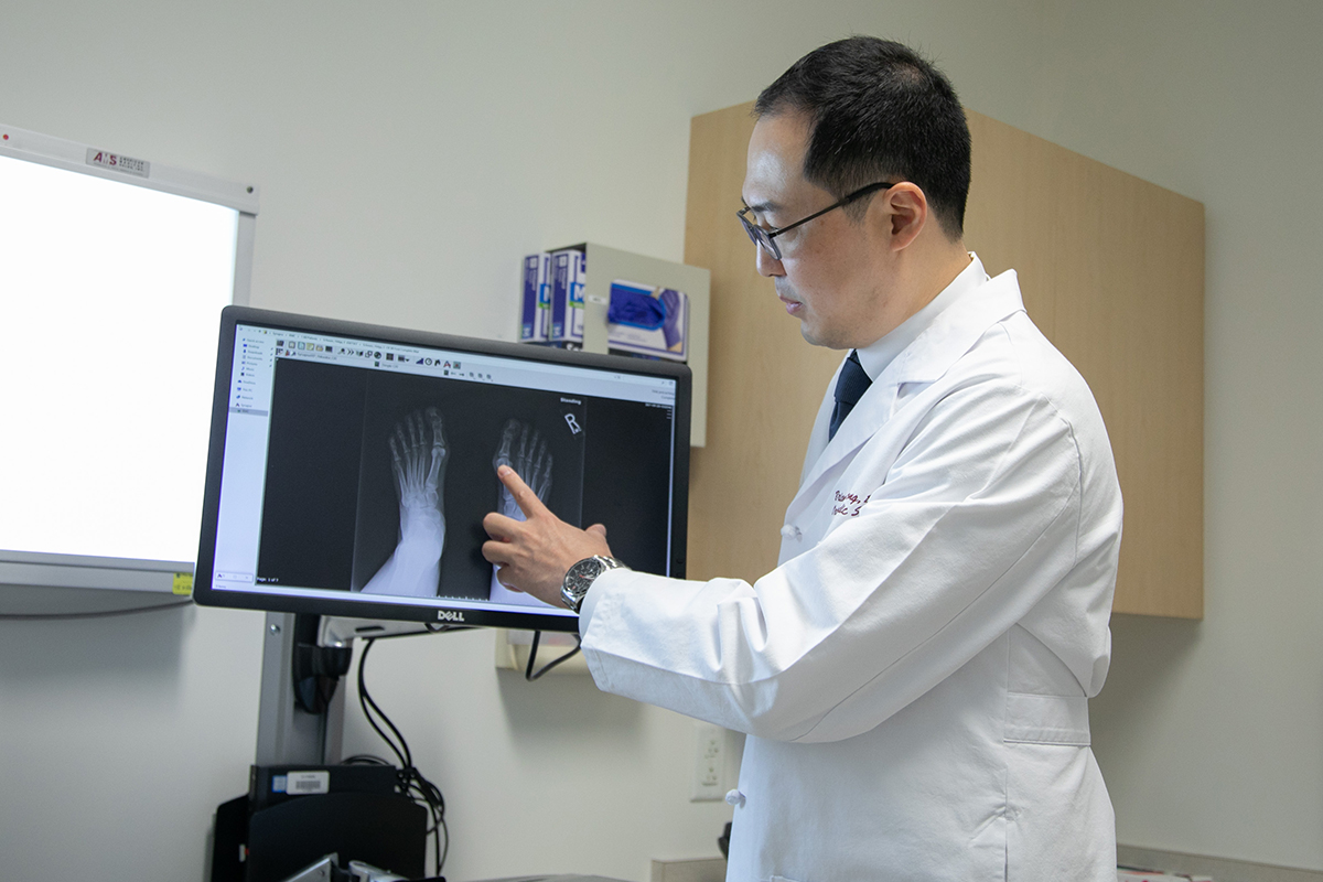 A foot and ankle specialist points to an X-ray in an exam room