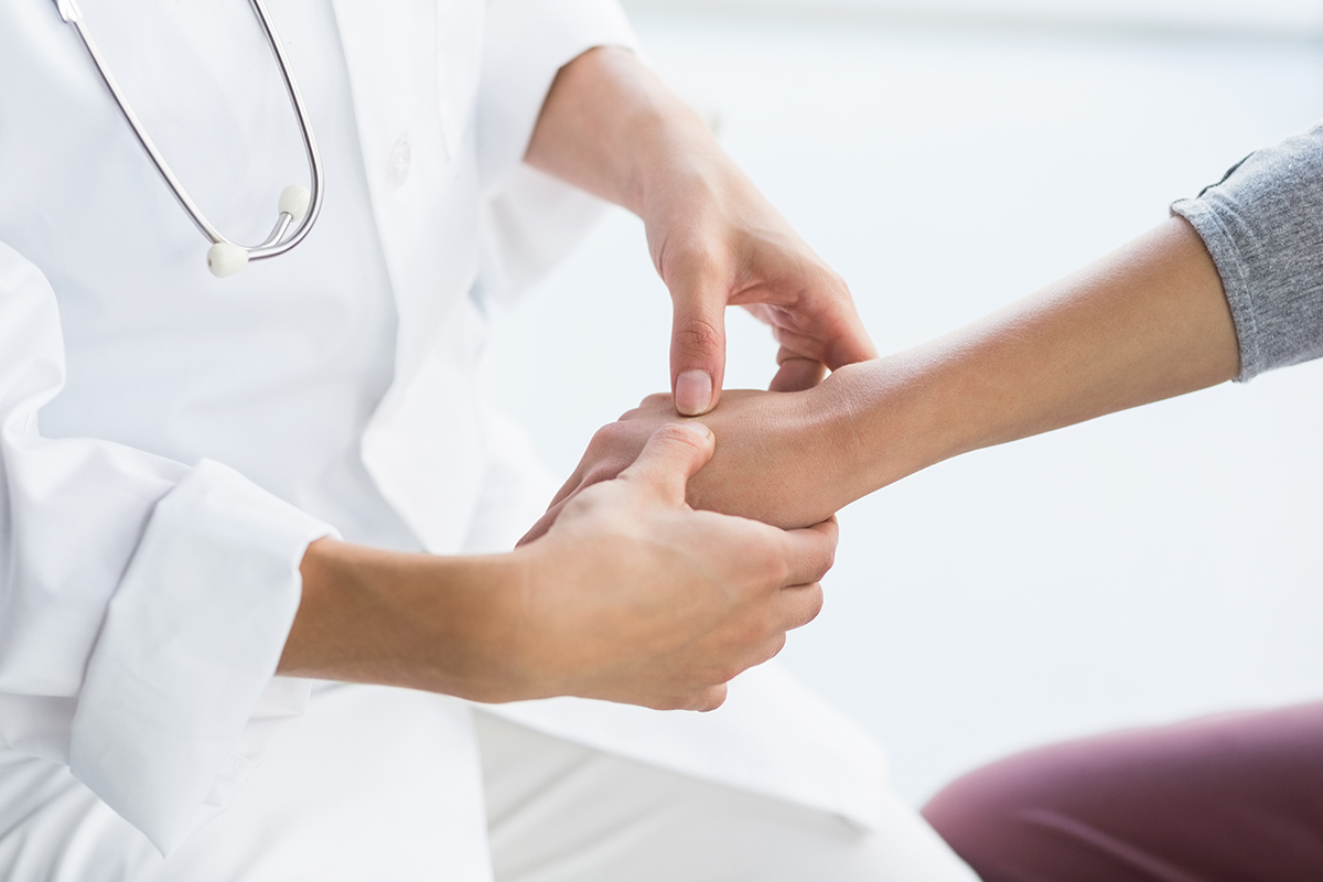 A Keck Medicine of USC hand specialist in white clothes examines a patient's hand injury