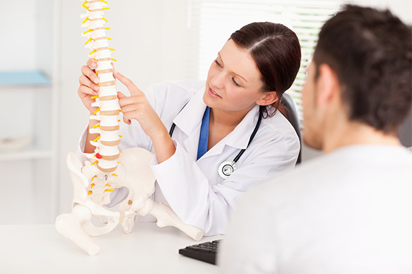 Female doctor points to a bone in spine.