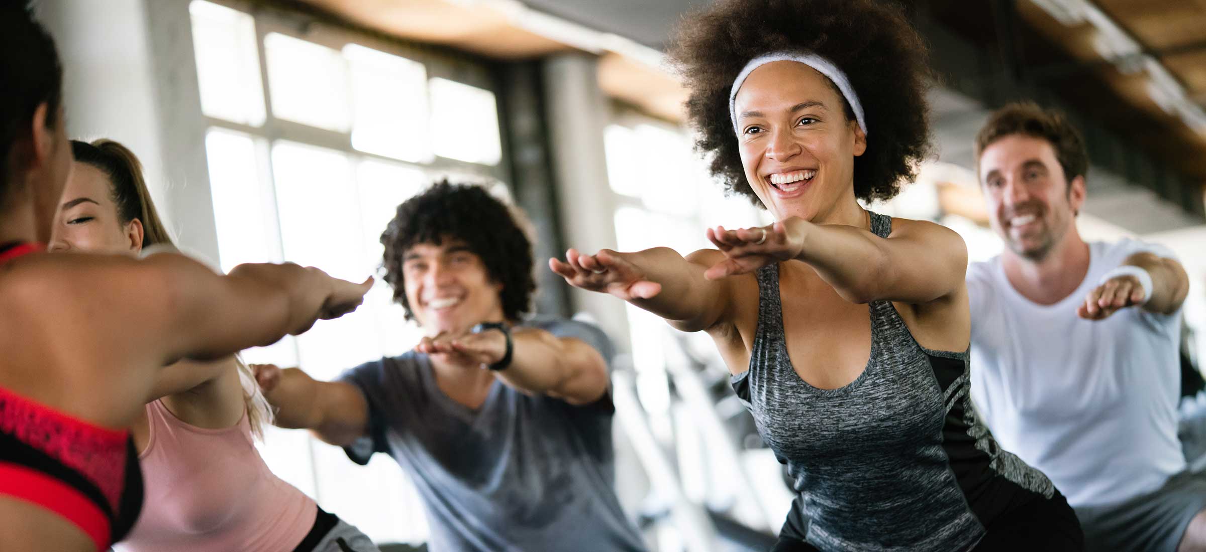 A group of people bend and put their arms out in a workout class in a fitness studio..