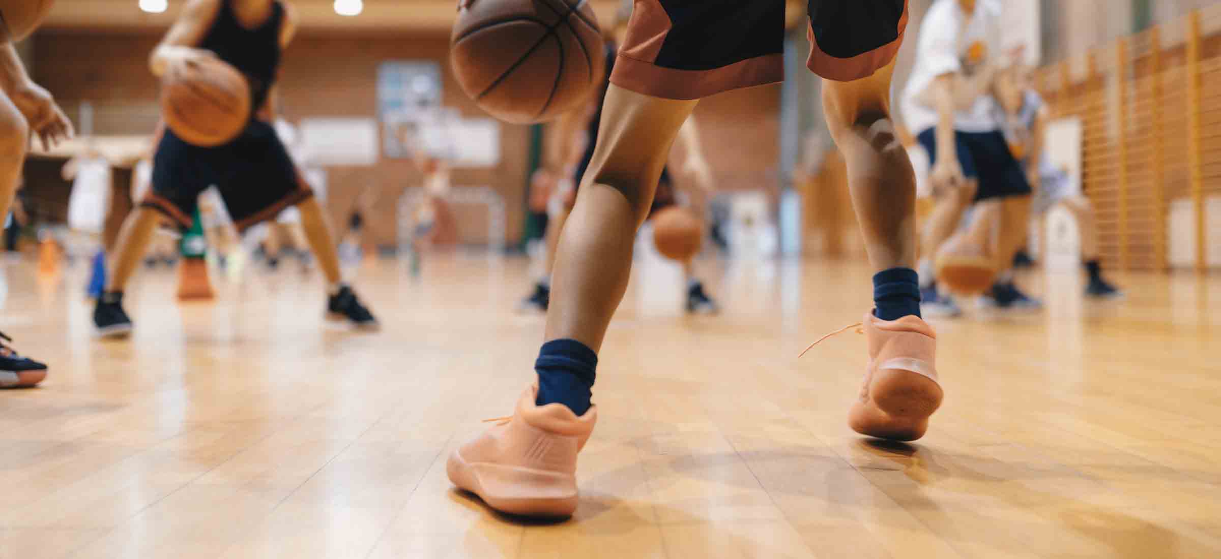 A close up shot of a man's legs playing basketball on a court with other players.