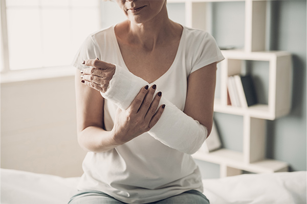A woman holds her arm in a cast.