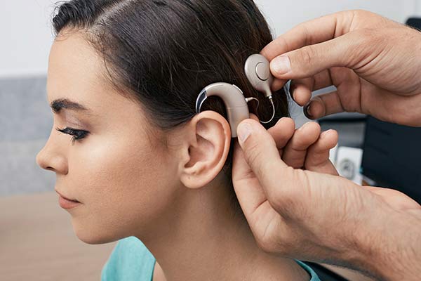 A doctor adjusts a hearing implant on a woman's head.