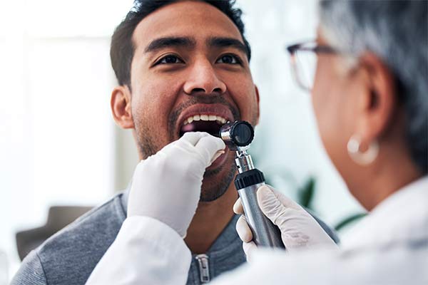 A doctor puts an instrument in a patient's throat.