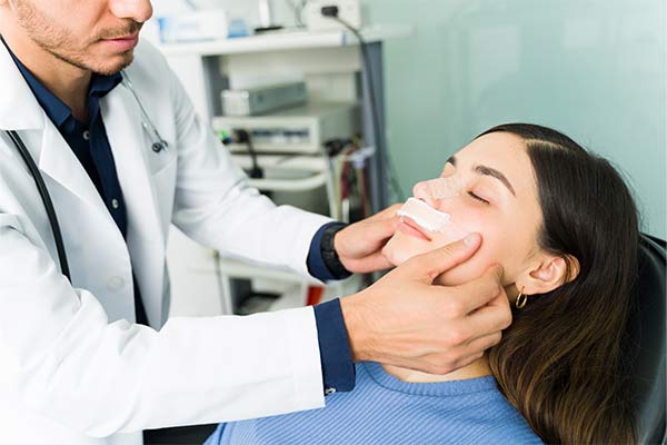 A doctor puts tape near a patient's nostrils.