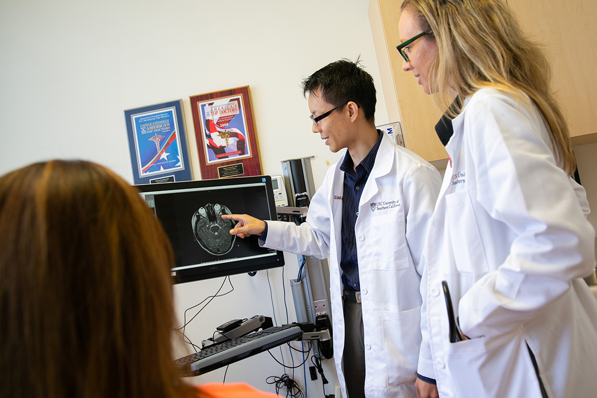 Two physicians examining a brain scan on a monitor