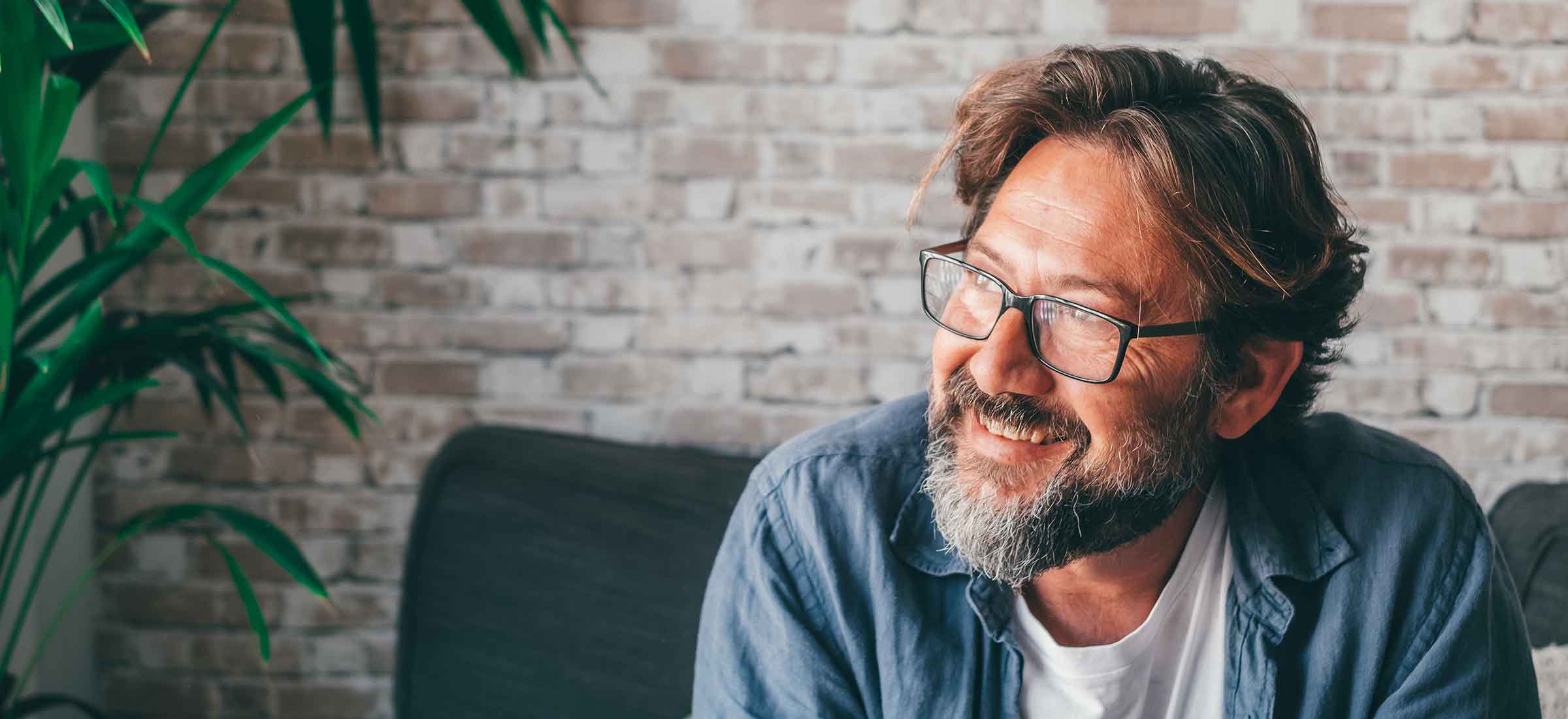 A man smiles while sitting on a couch.