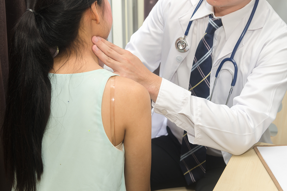 A male head and neck surgeon feels the neck of a female patient during a throat cancer exam