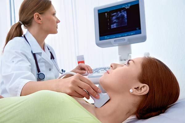 A doctor performs an ultrasound on a woman's thyroid.