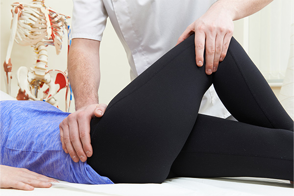 A doctor holds on to female patient's knee and hip.