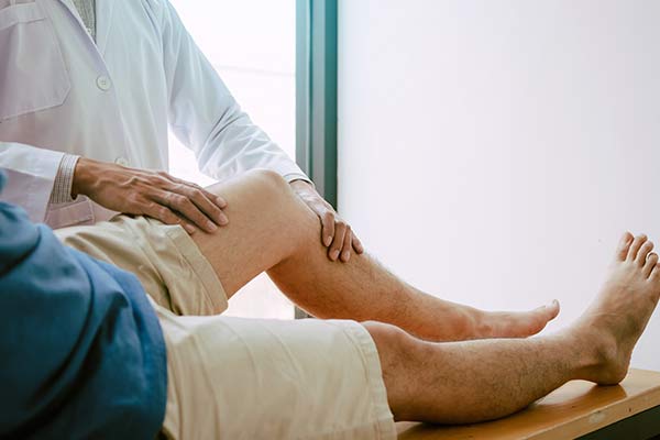 A doctor holds a man's knee as he lies on a medical table.