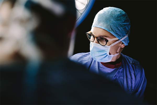 A surgeon looks into the light with a dark background.