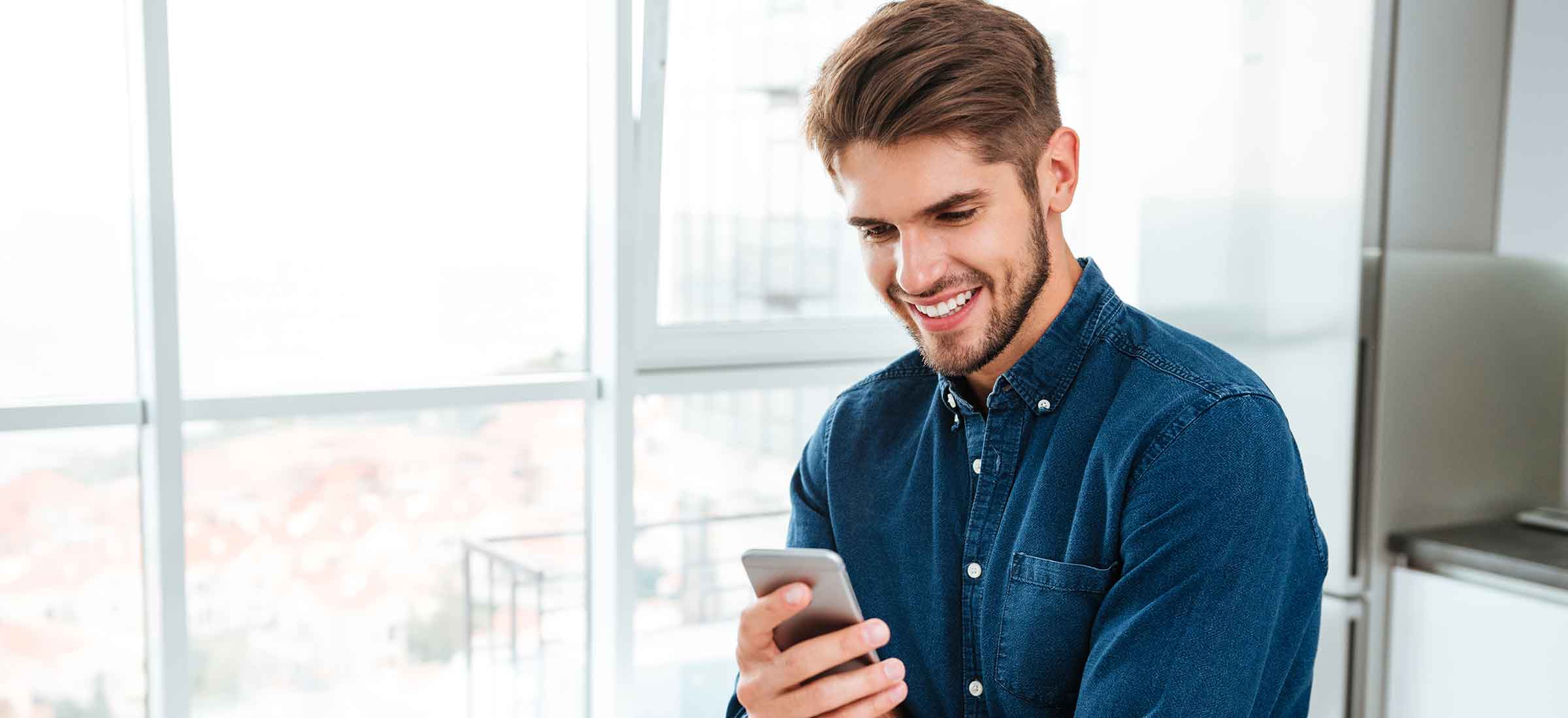 A man smiles while he looks at his phone.