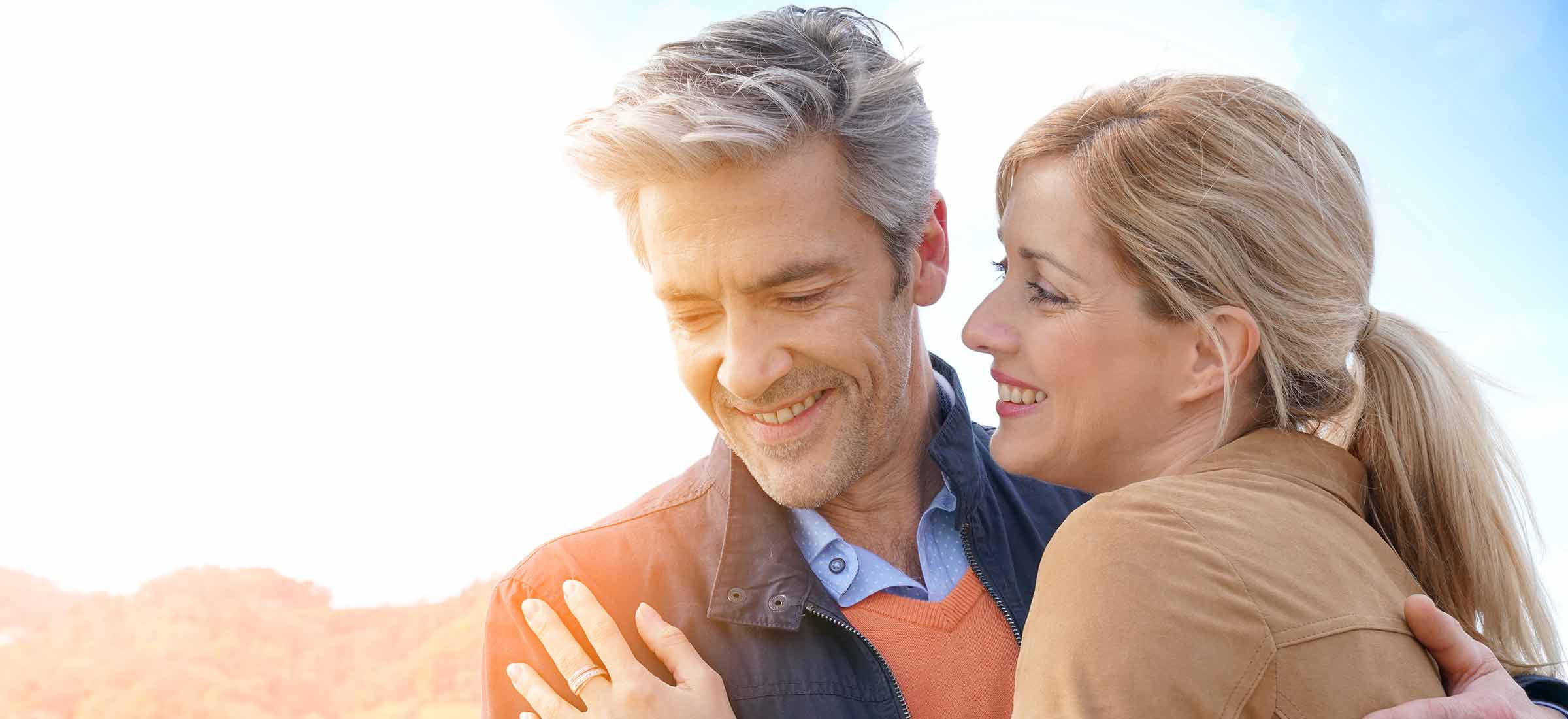 Middle-aged couple embracing each other by the sea.