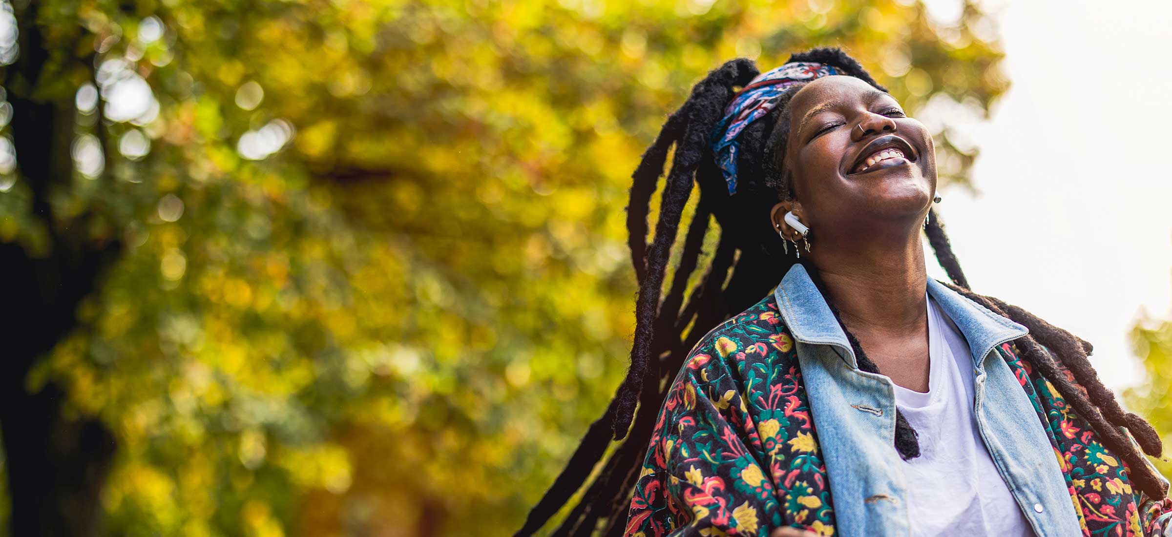 A woman smiles in a park while swinging her hair.