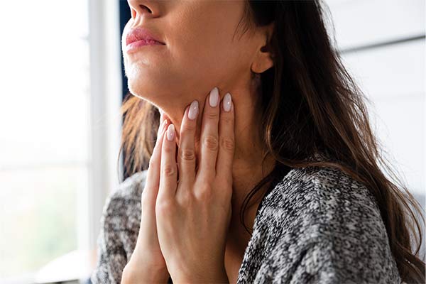 A woman touches her neck.