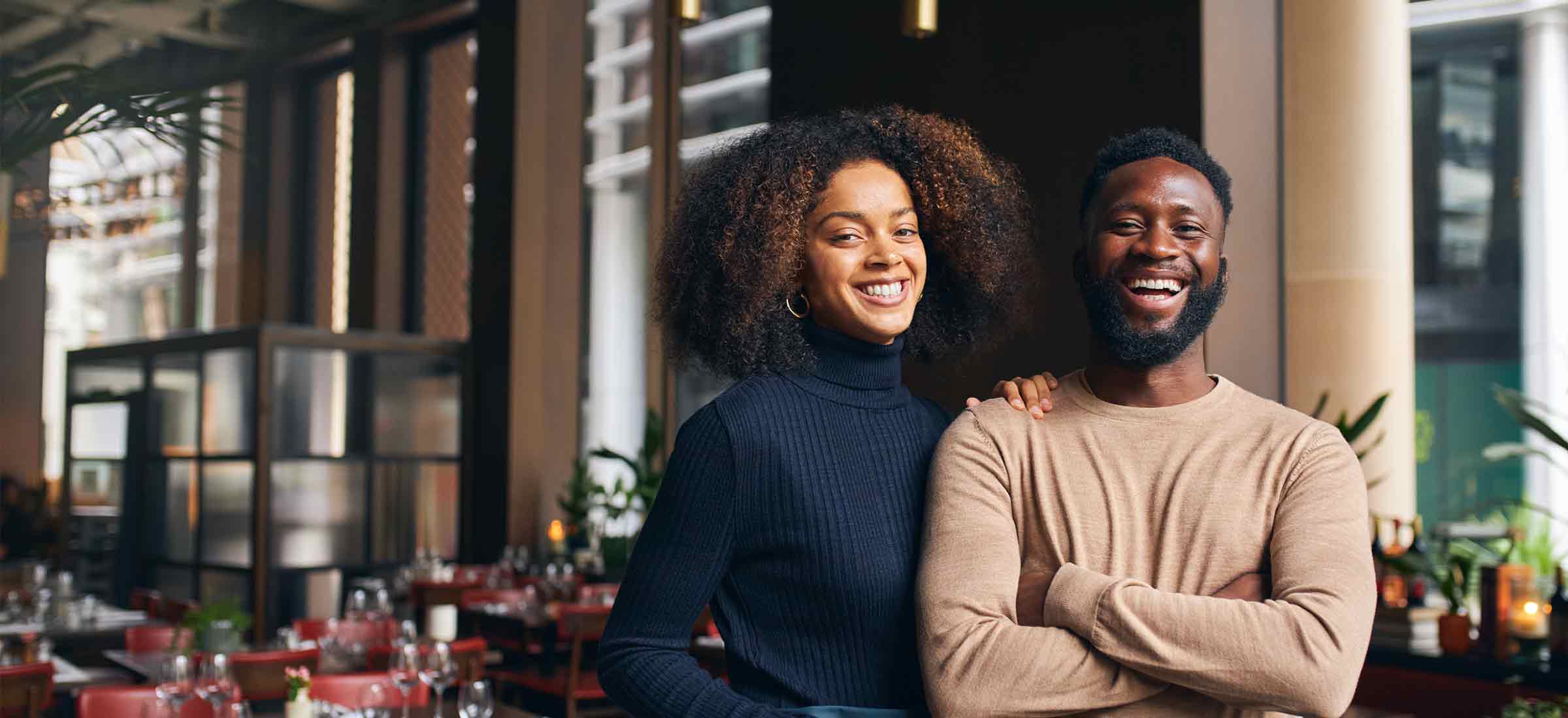 Cheerful small business partners stand in a restaurant.