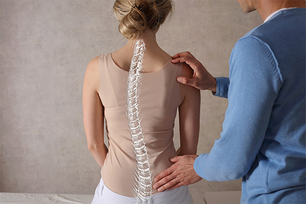 A female patient sits on a table with a graphic of her spine overlaid.