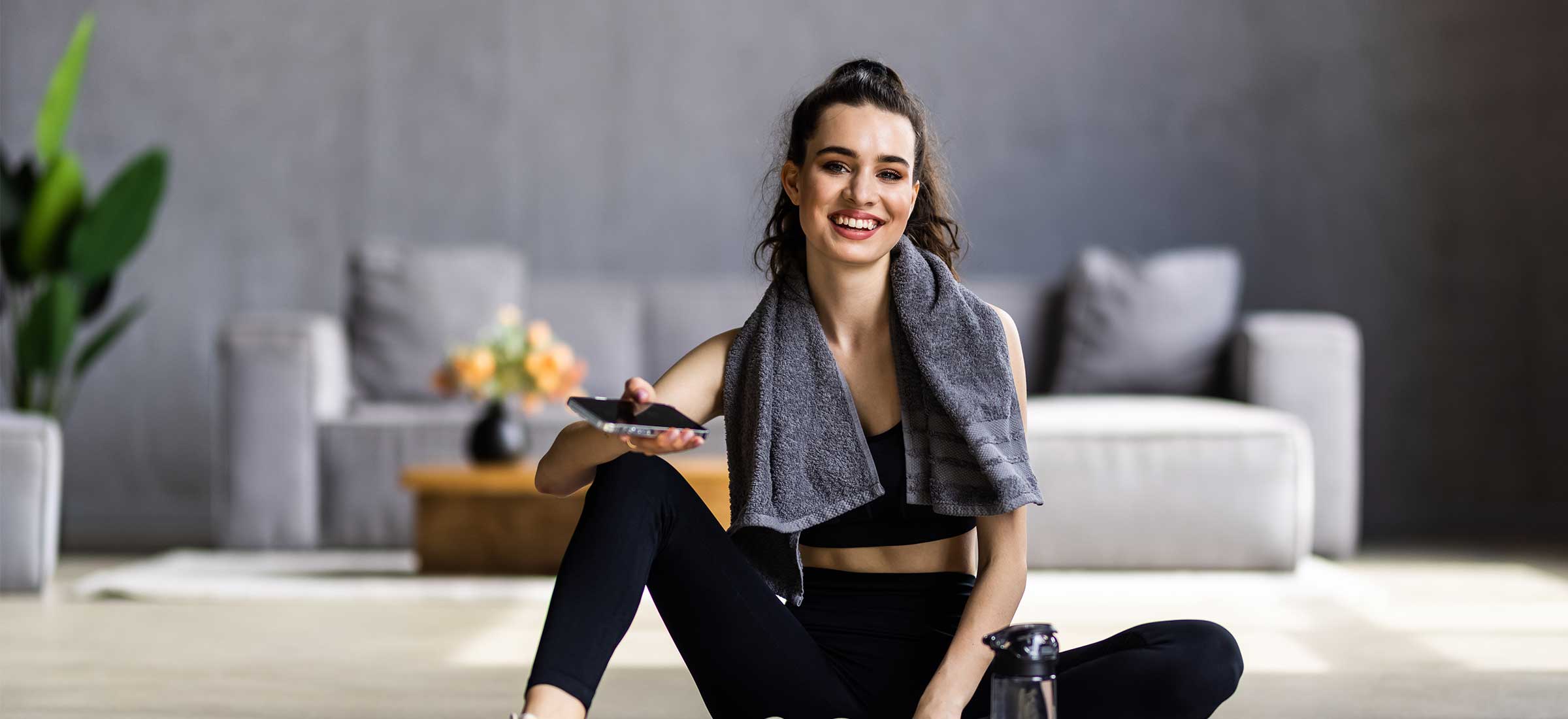 A satisfied fitness blogger rests after workout at home with water.