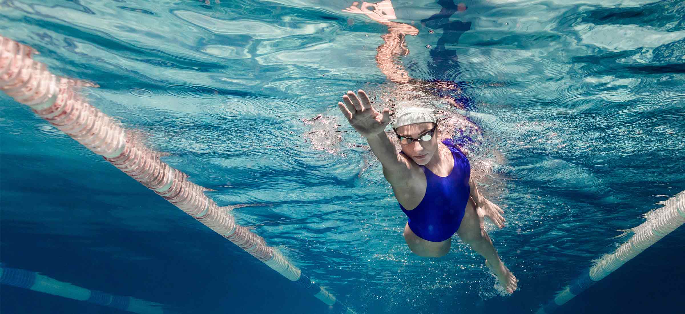 A woman swims freestyle through a pool.