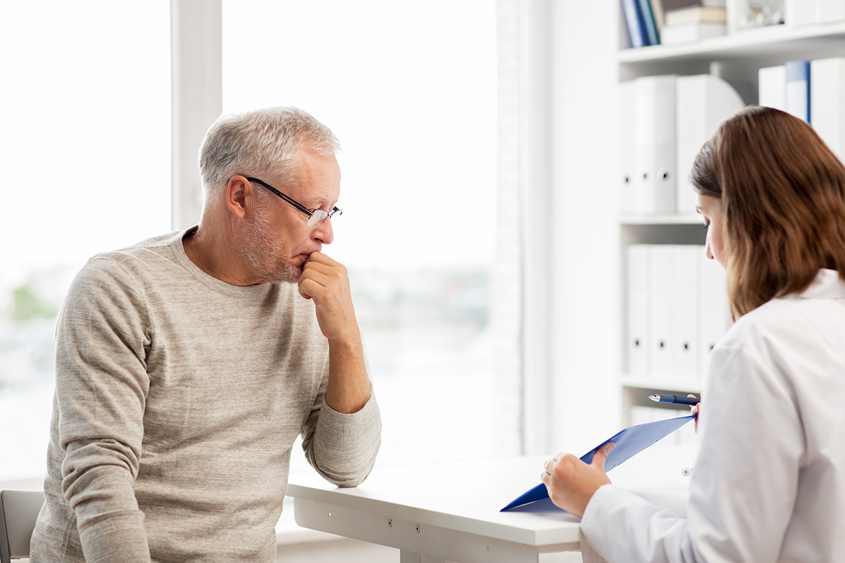A male patient sitting in a chair during a consultation with his doctor