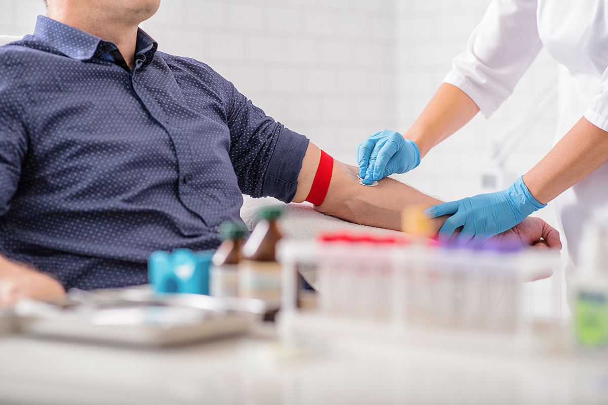 Medical care provider sanitizing a patient's forearm to draw a blood sample