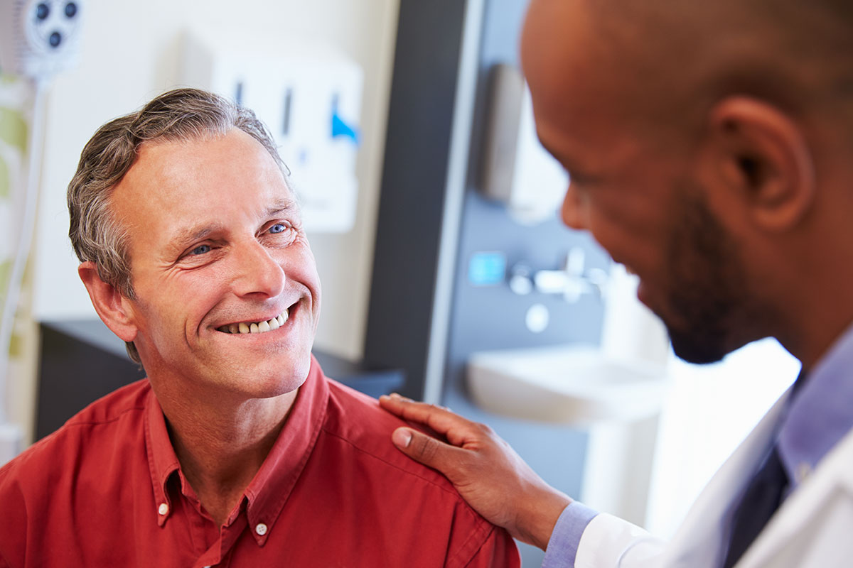 Male patient being reassured by doctor in hospital room.