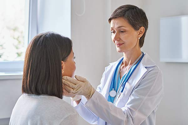 A doctor touches a patient's neck.