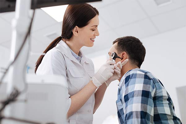 A doctor holds an instrument to look in a man's ear.