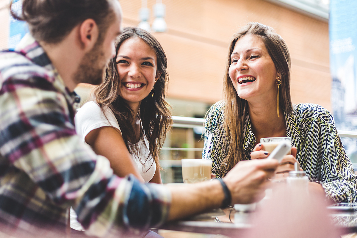 A young man and two young women trigeminal neuralgia and hemifacial spasm patients smile and laugh at a coffee bar