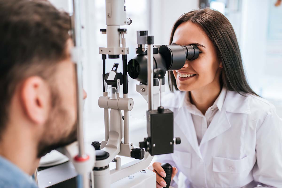 A female Keck Medicine LASIK eye surgery expert examines a male patient for eye treatment in a vision center
