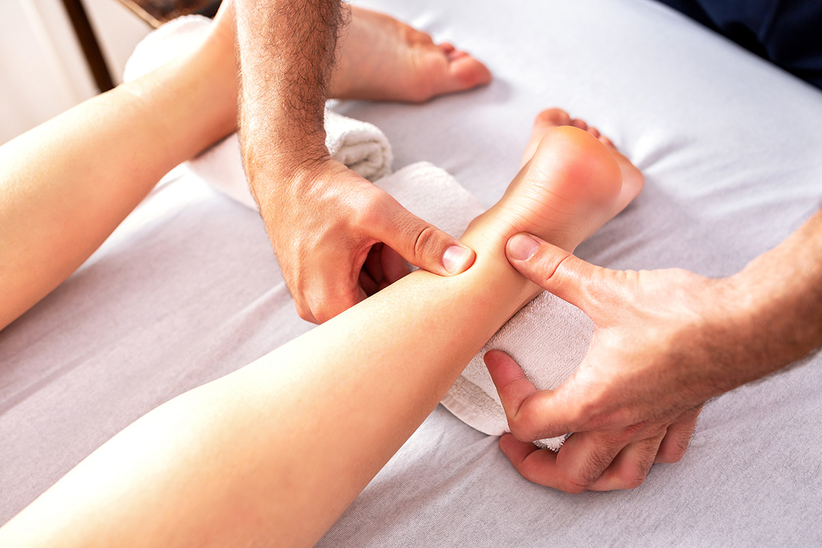 A Keck Medicine physical therapist provides Achilles heel treatment to female patient with heel pain lying down