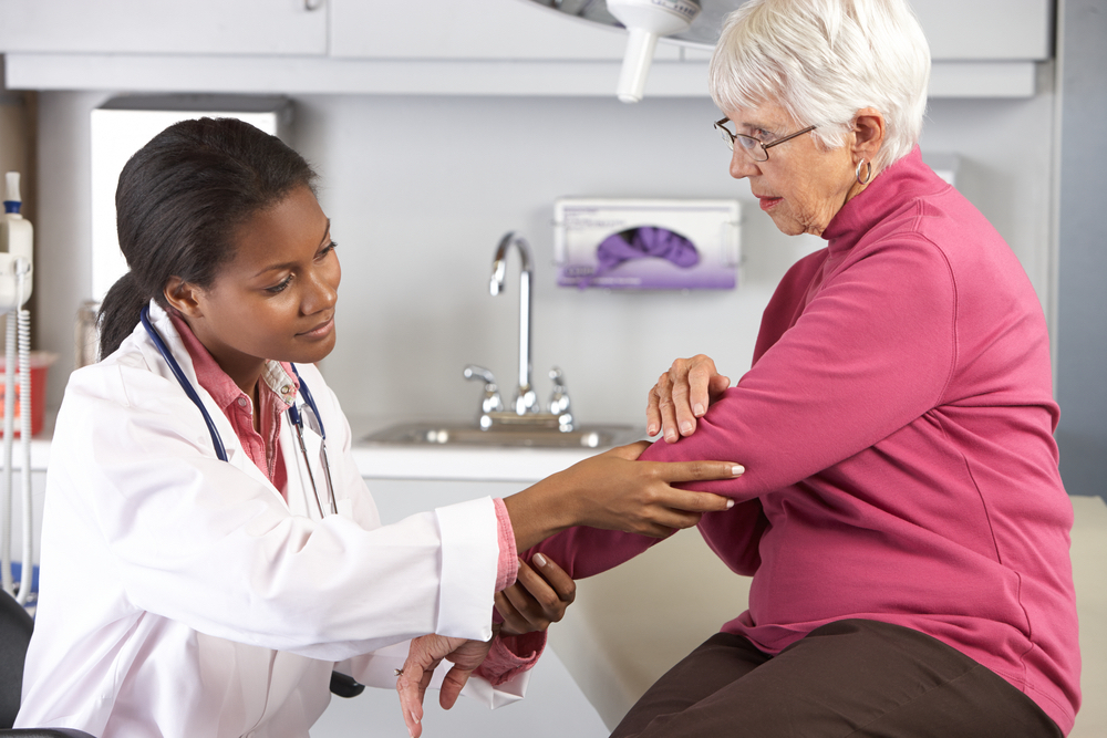 A female Keck Medicine lymphedema therapist examines the swelling of a senior female's arm in a medical setting