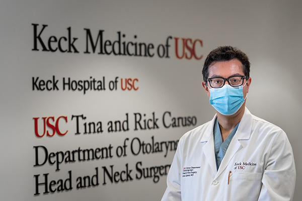 Dr. John Oghalai, a head and neck surgeon at Keck Medicine of USC who treats skull base tumors, wears glasses and a mask.