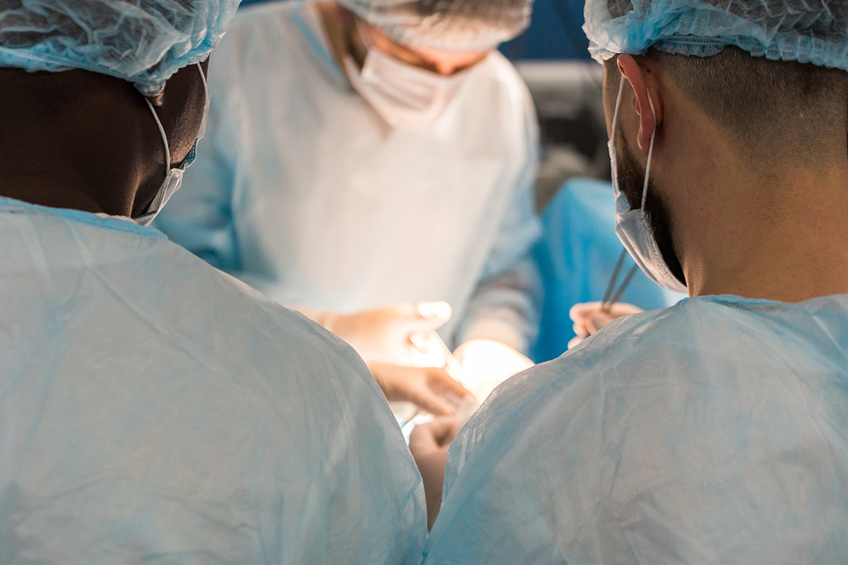 Three Keck Medicine of USC doctors in surgical gear perform plastic surgery in an operating room