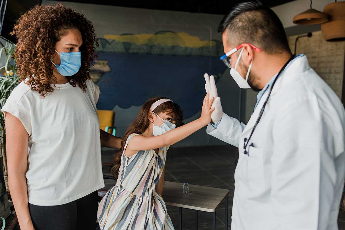 Young hispanic doctor vaccinating little girl at home.