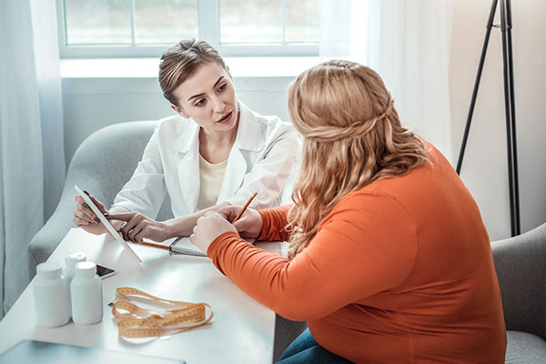 A doctor consults her patient at a table.