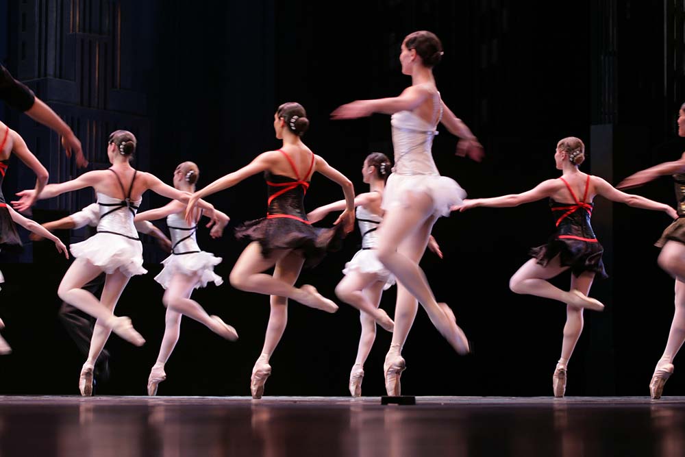 A group of ballerinas performing on stage in a theatre.