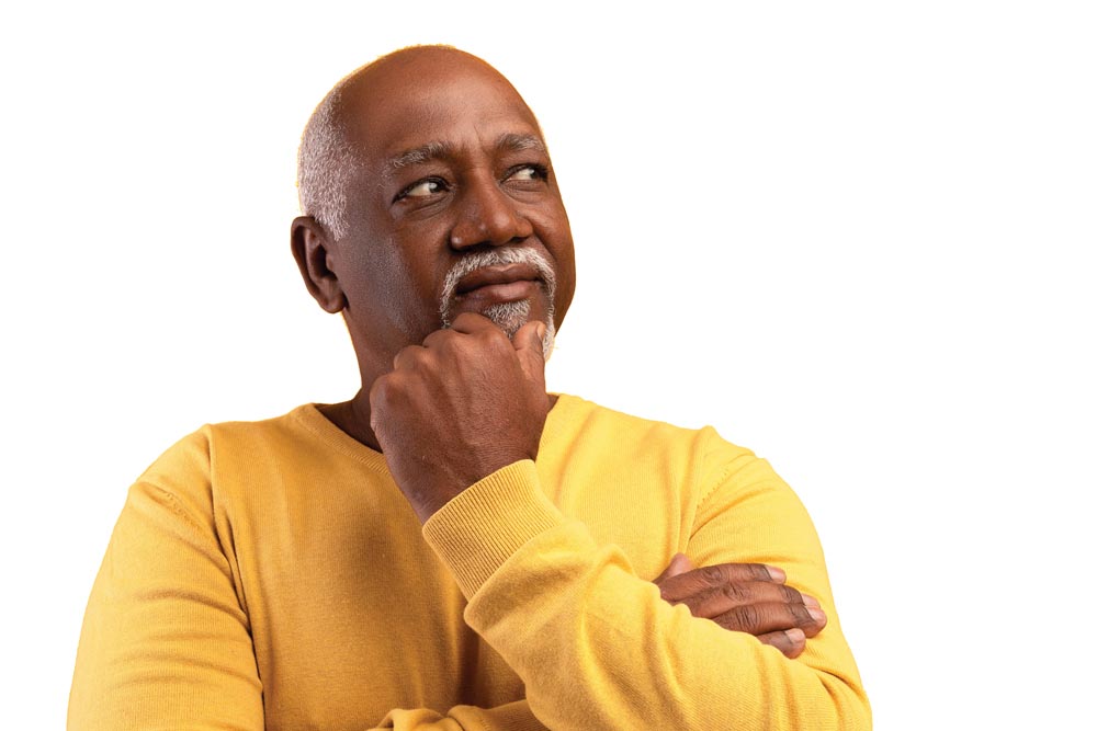 Older Black man looking aside at empty space, touching his chin, deep in thought