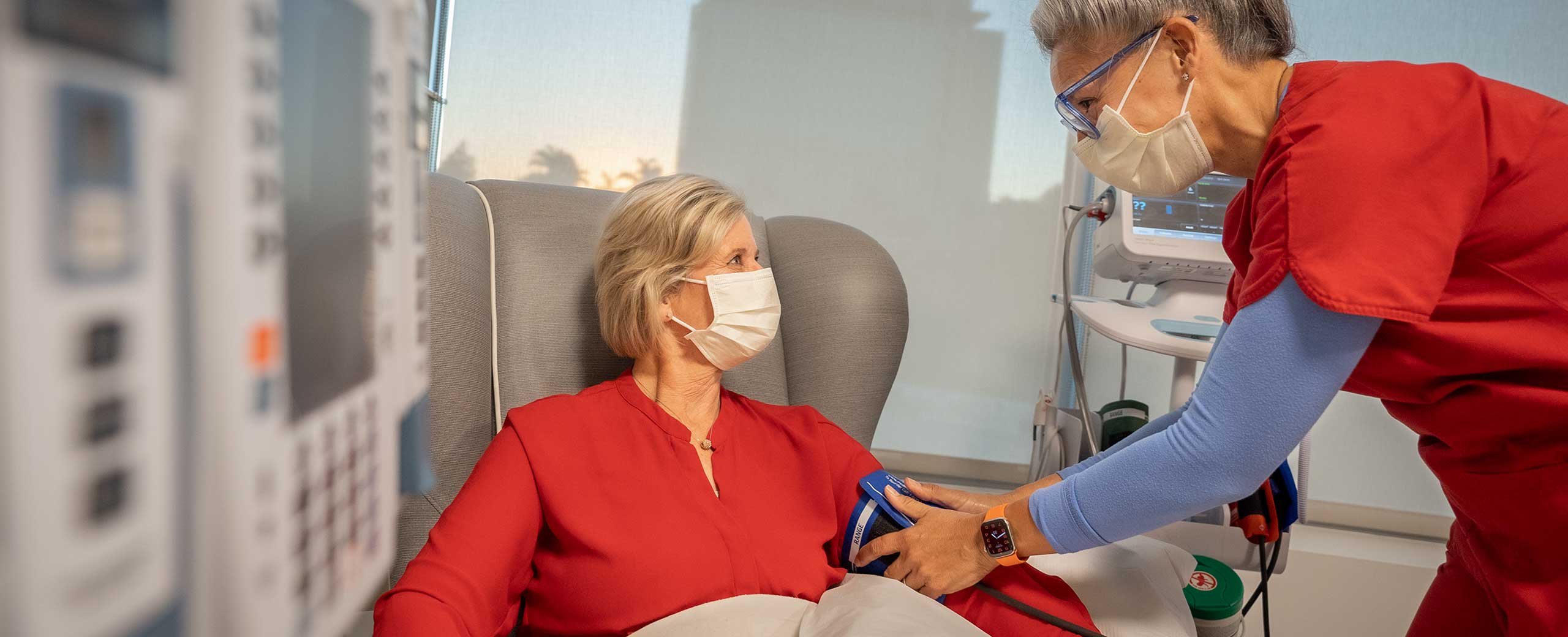 A female health care provider monitors a female patient in a medical exam room
