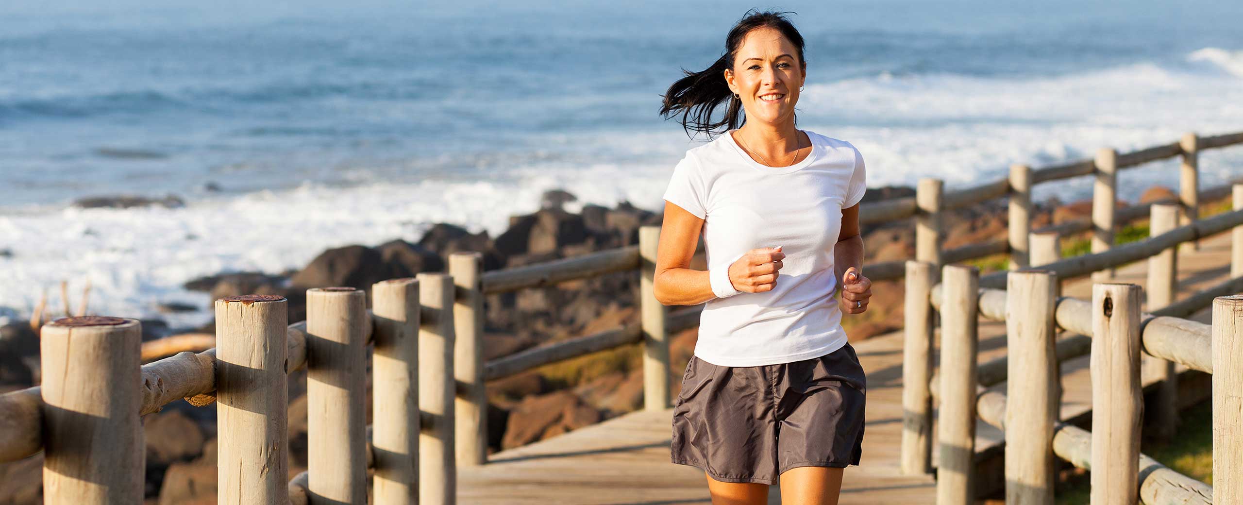 Woman running on a dock by the beach