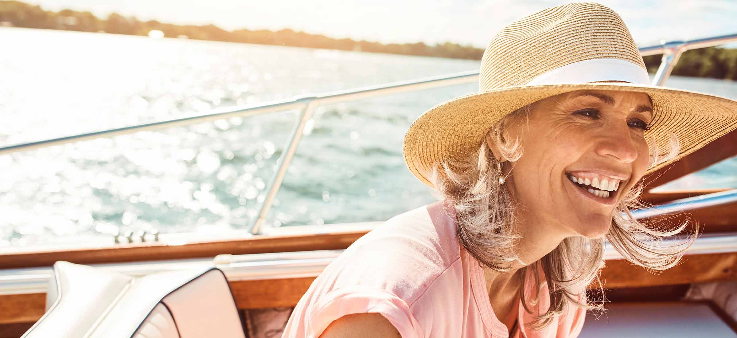 A woman in a sun hat smiles on a boat.