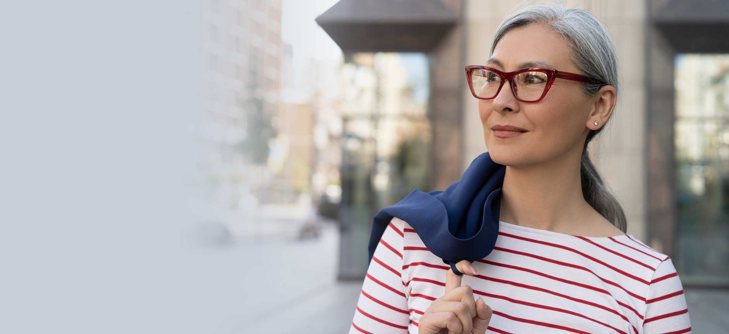A person in red glasses wearing striped clothing in the city