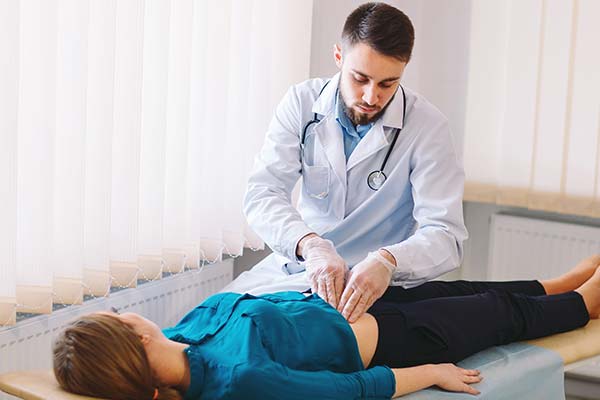 Patient lying down in a hospital bed while doctor examines the patient's abdomen