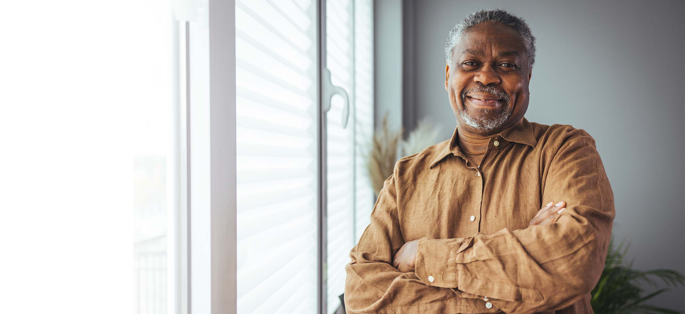 A person smiling while standing by a window