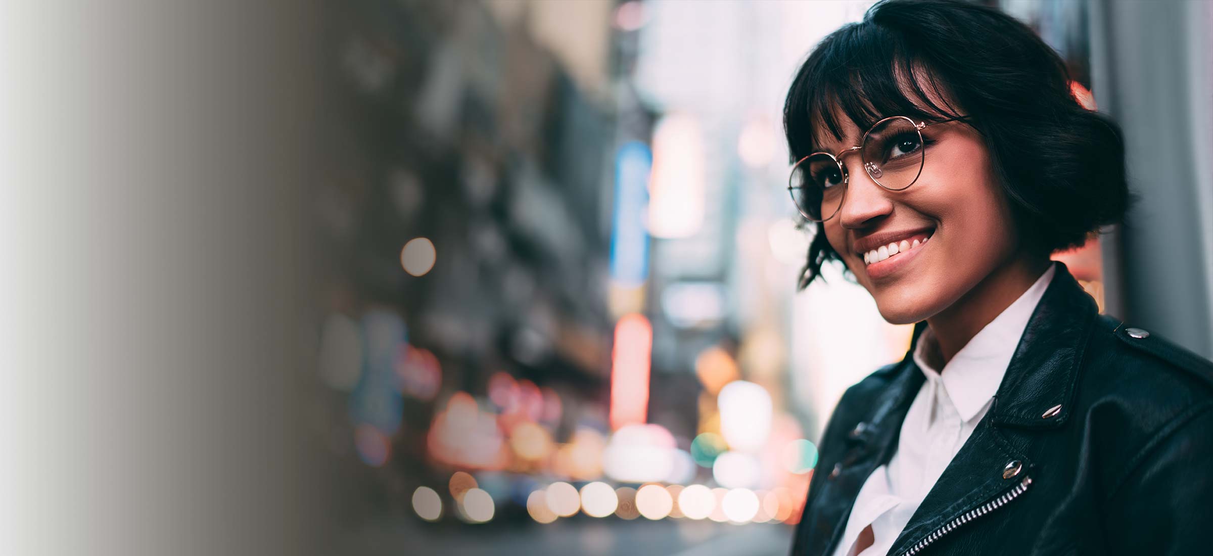 Person wearing glasses smiling in a city