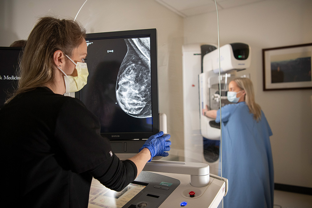 Scientist and researcher for breast cancer clinical trial looking at specimen through microscope.