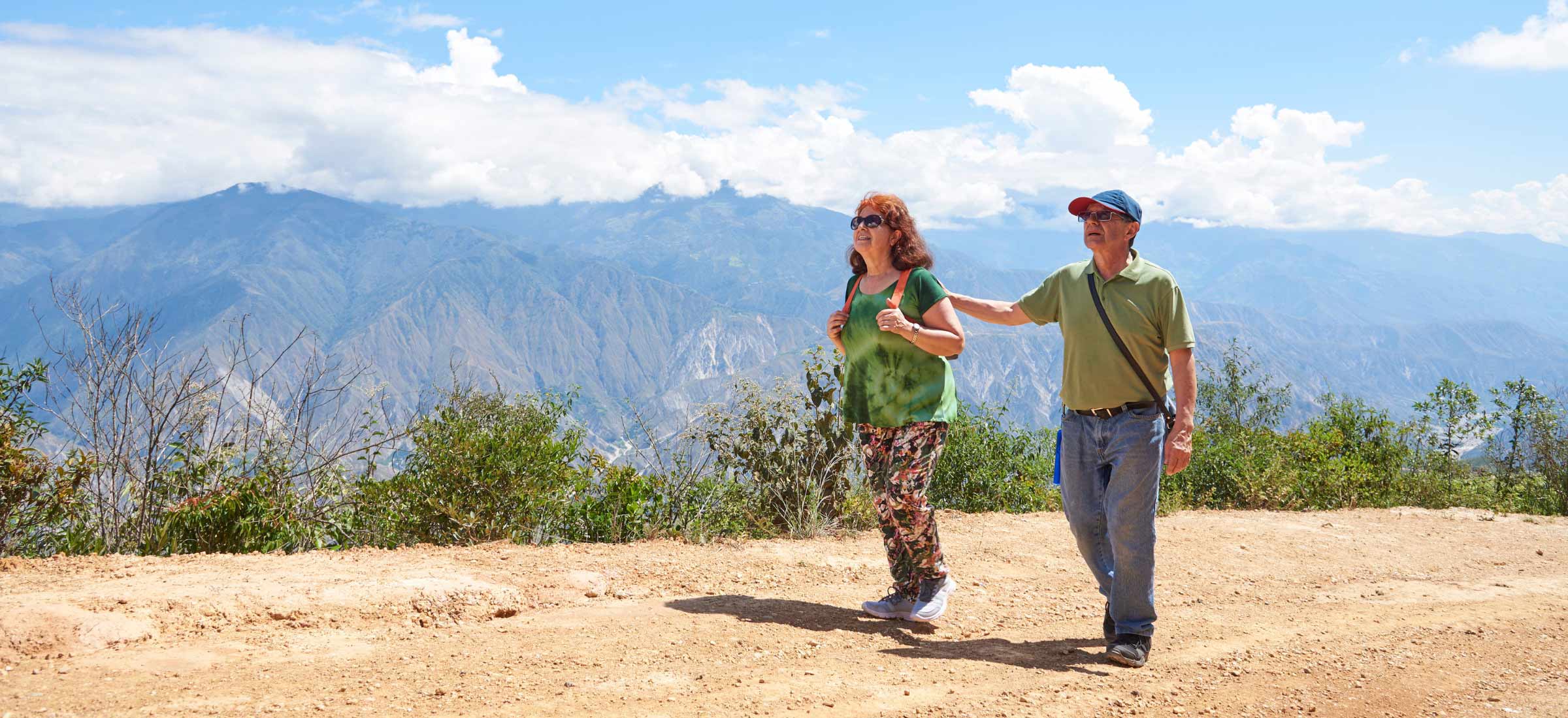 An older couple hiking on a hilltop looking out towards the horizon